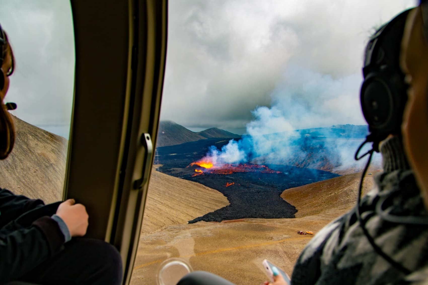 Passengers in a helicopter looking down at an erupting volcano in Iceland