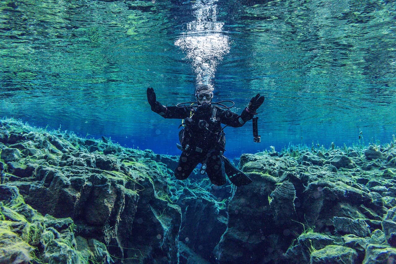 Diver swimming through clear glacial water in Iceland