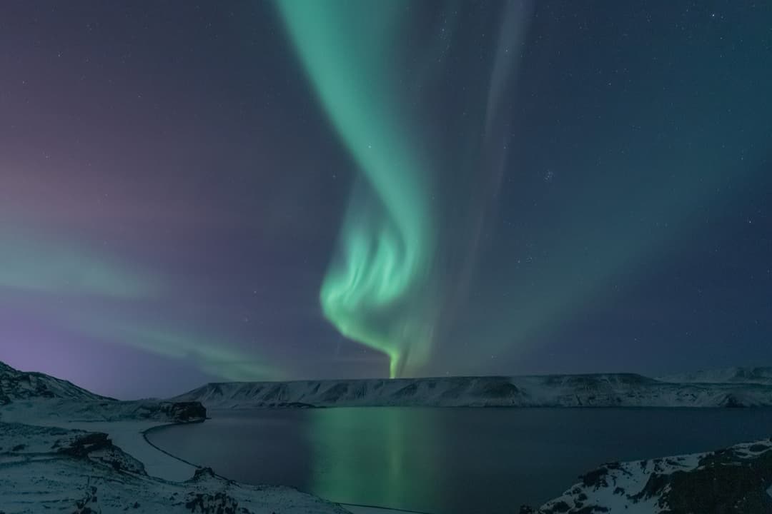 Aurora reflected in a still lake ringed by snow