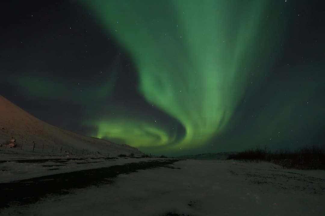 Aurora arcing over a snow covered road in Iceland